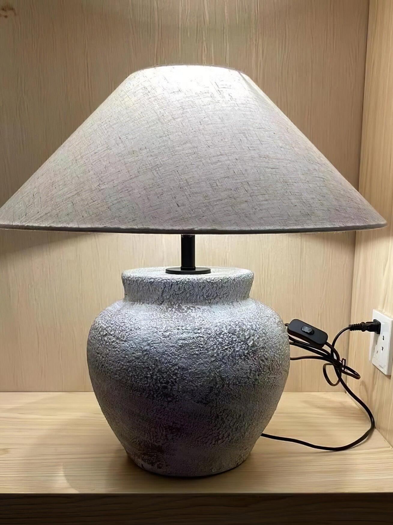 Textured urn lamp and cord on wooden shelf