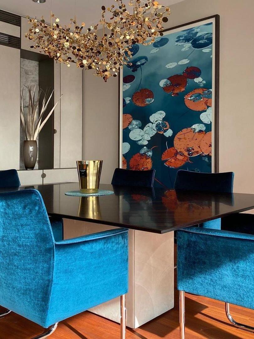 Long gold disc chandelier above a table with blue chairs