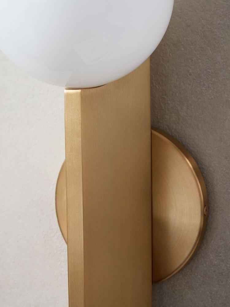 Close view of white globe junction, gold-colour blade and circular wall plate on a textured wall