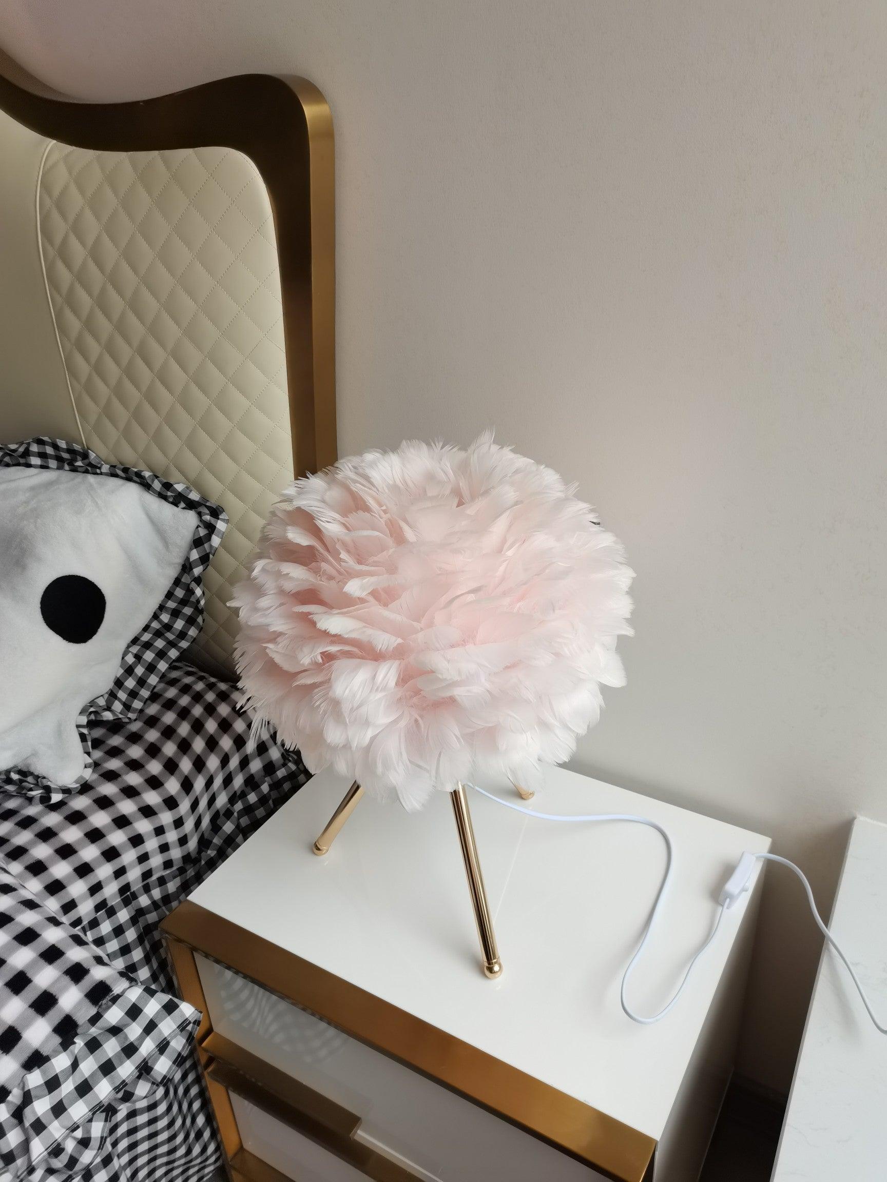 Pale pink feather lamp beside bed and white cable