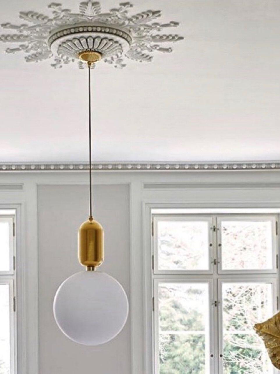 White globe pendant beneath a decorative ceiling rose