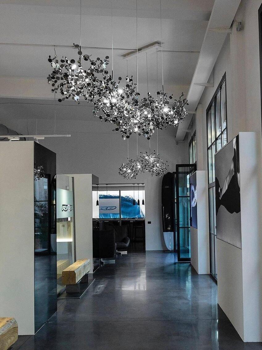 Long silver disc chandelier beside tall windows
