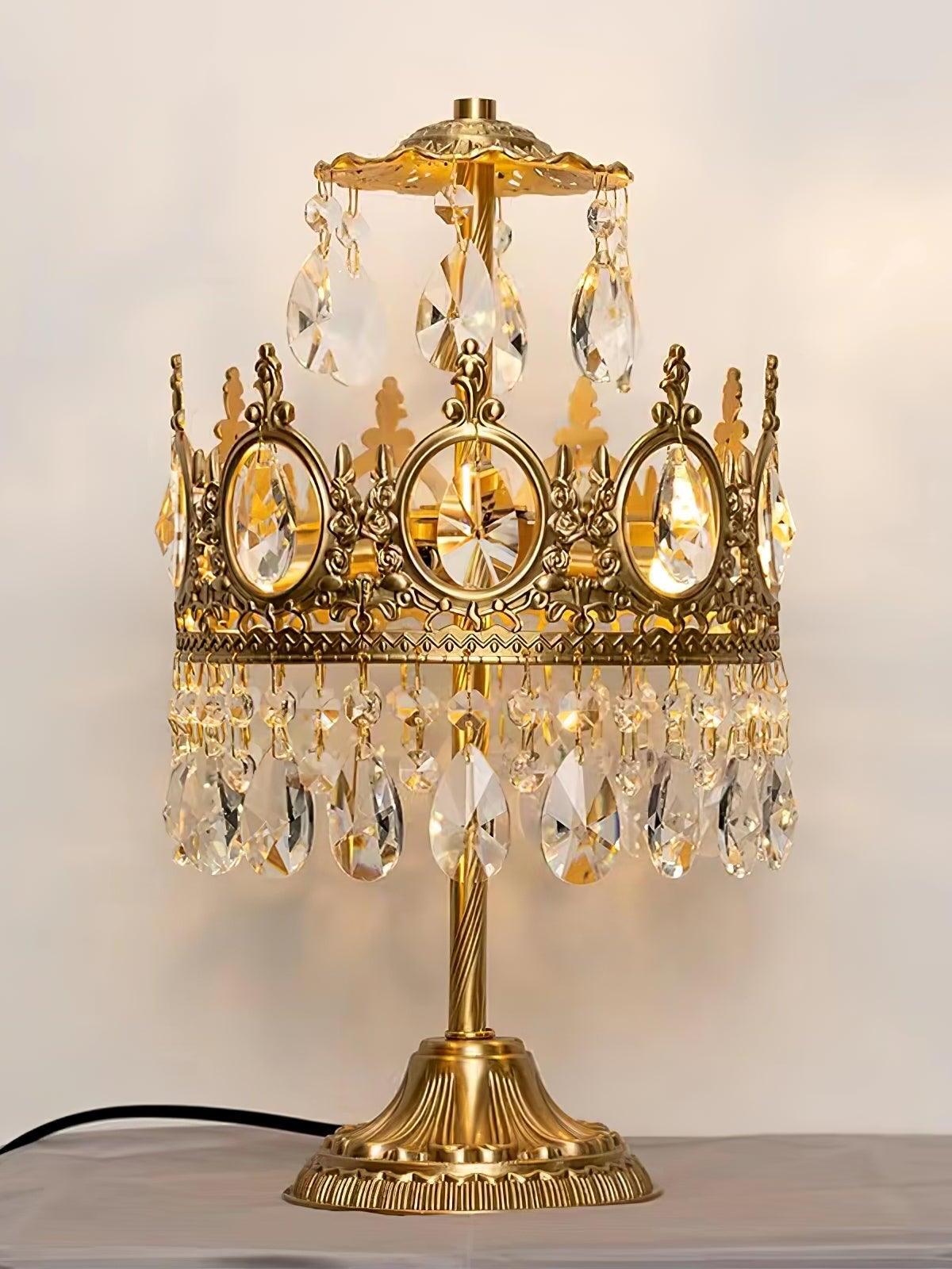 Crystal table lamp on a pale tabletop, showing upper hanging drops, oval crown details and a black cord.
