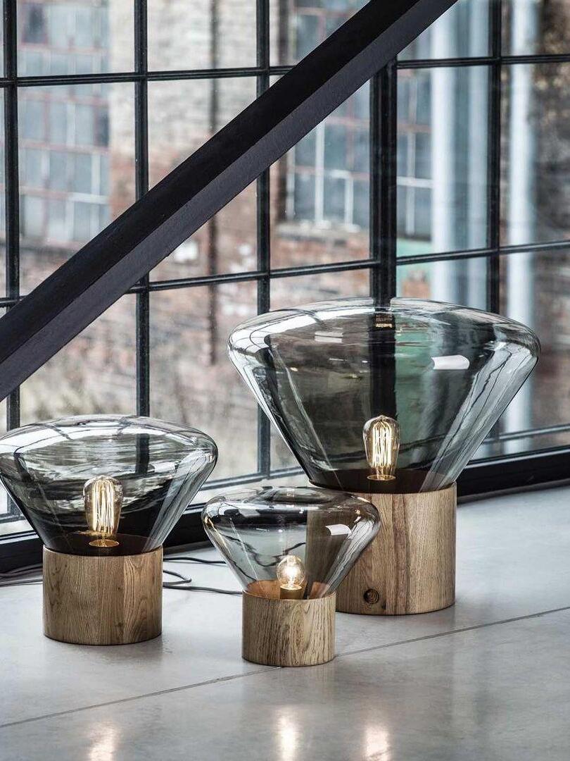 Three smoky flared glass lamps of different apparent sizes at window ledge