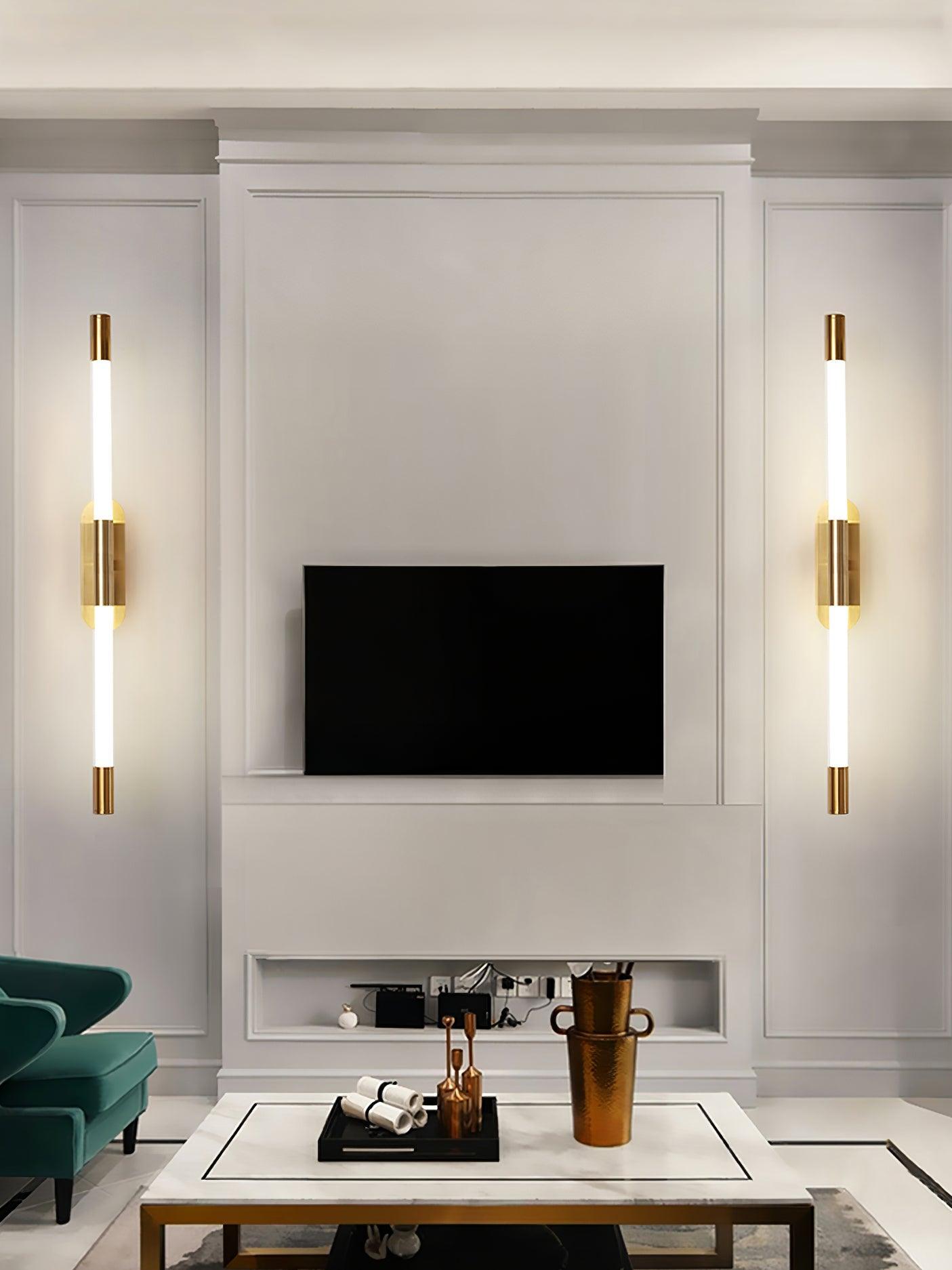 Two vertical gold Agnes wall lights flanking a television above a living-room table