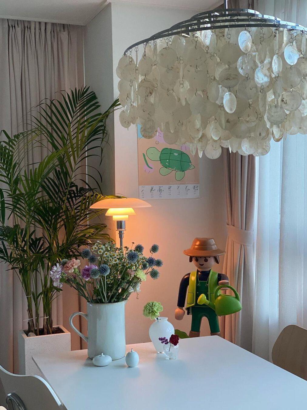 Close view of white shell discs above a desk with toys, flowers and plants