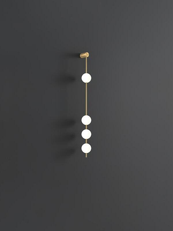 Four-globe gold-colour wall lamp with one upper globe and three lower globes against dark grey