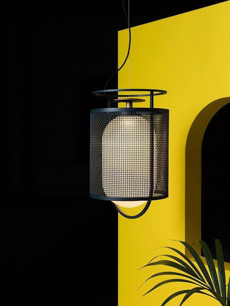 Black mesh lantern pendant against yellow and dark backdrop