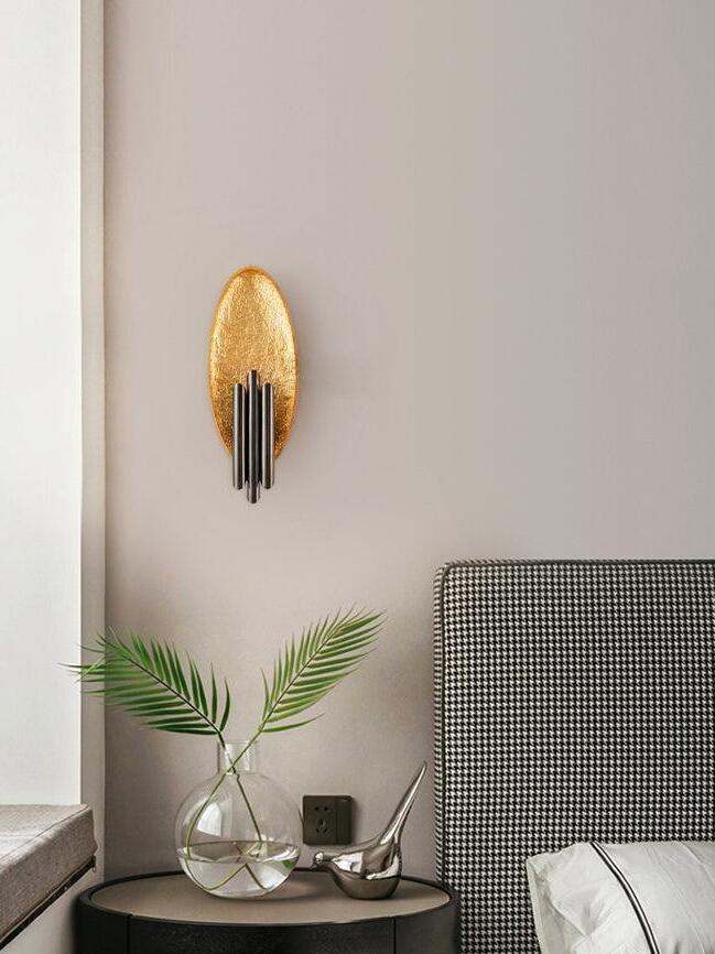 Gold-tone oval sconce above side table with green leaves