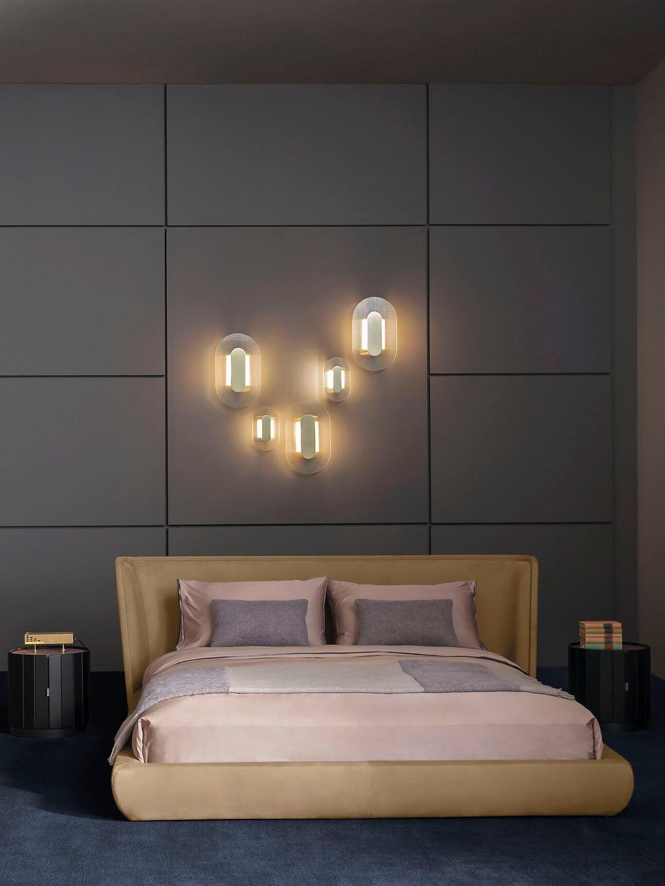 Five elongated Button wall lights above a mustard-coloured bed against grey rectangular wall panels