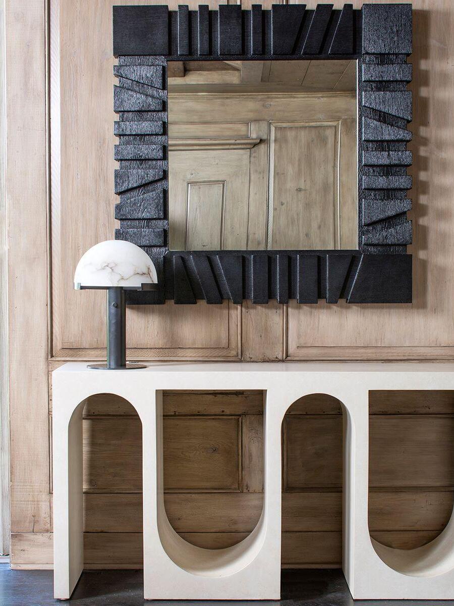 Black column lamp on a console beneath a mirror