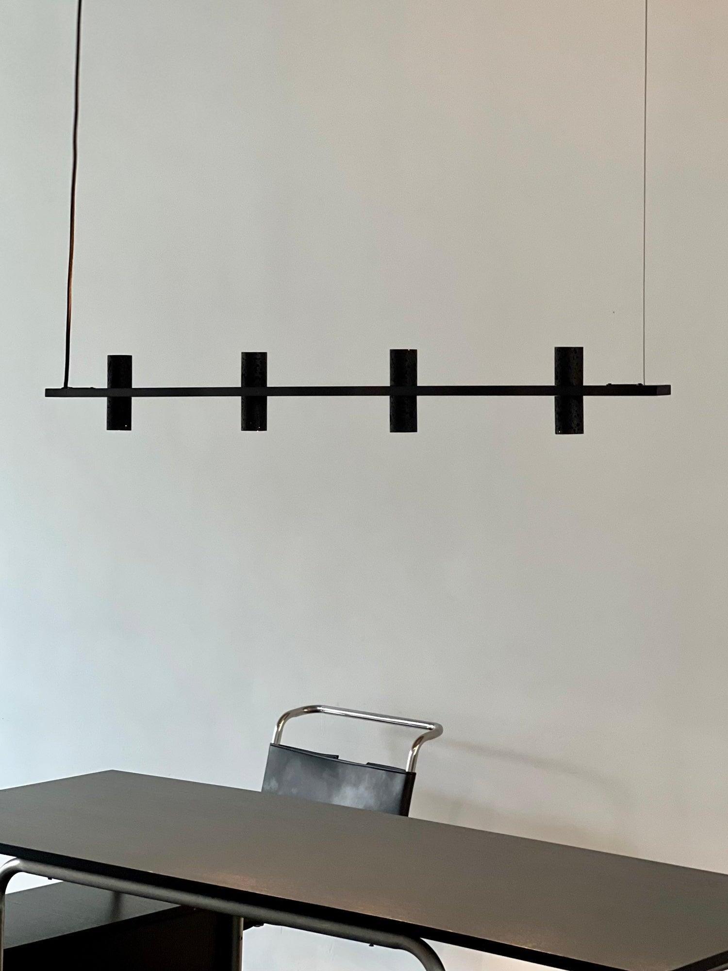 Four-cylinder bar pendant above a dark table