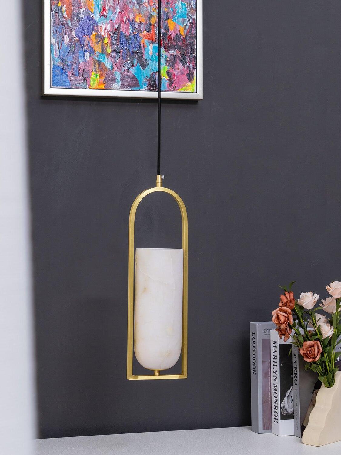 Unlit Melange stone shade and arched frame beside books and flowers against a dark wall