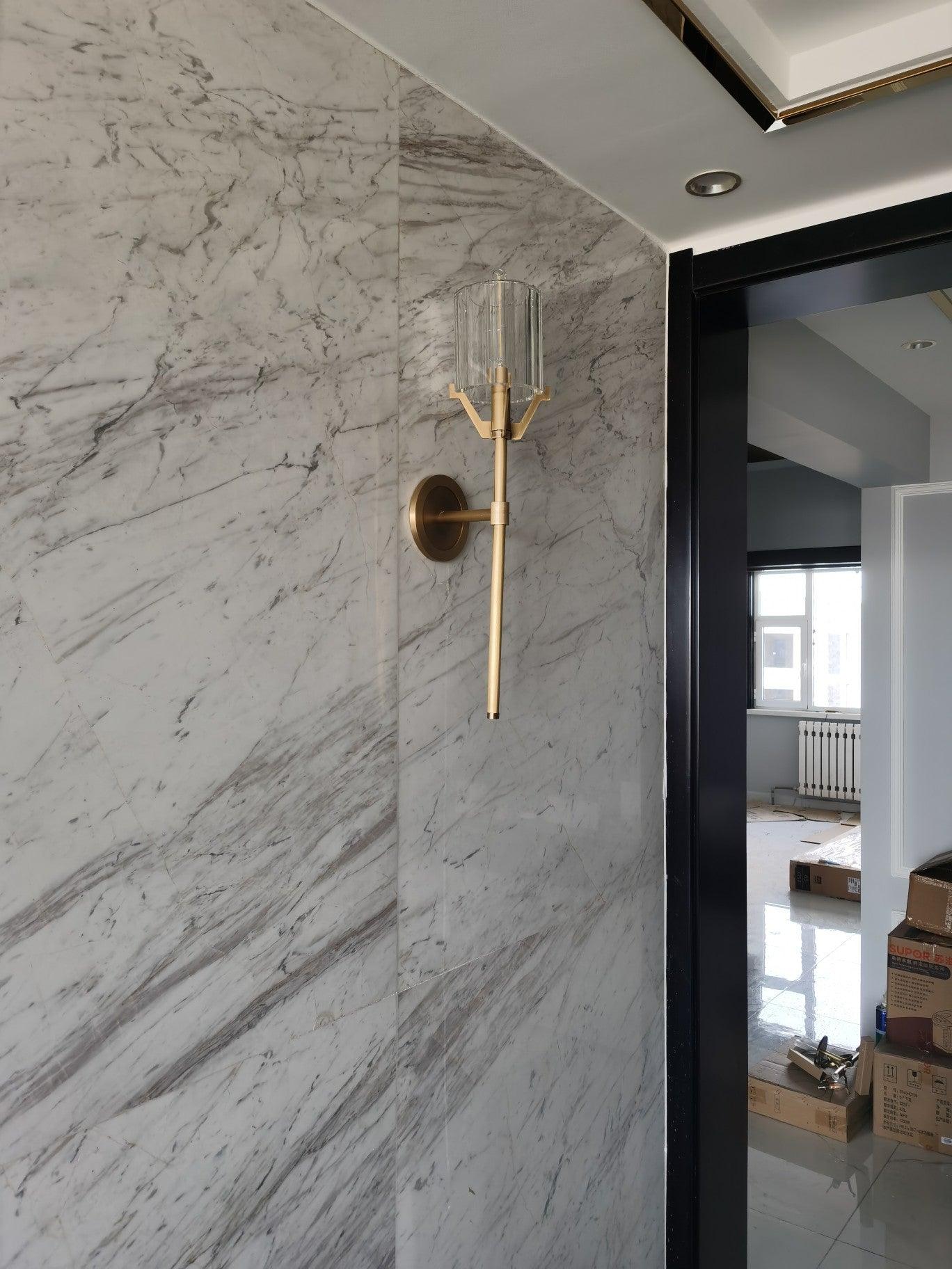 Gold sconce installed on a marble-patterned interior wall
