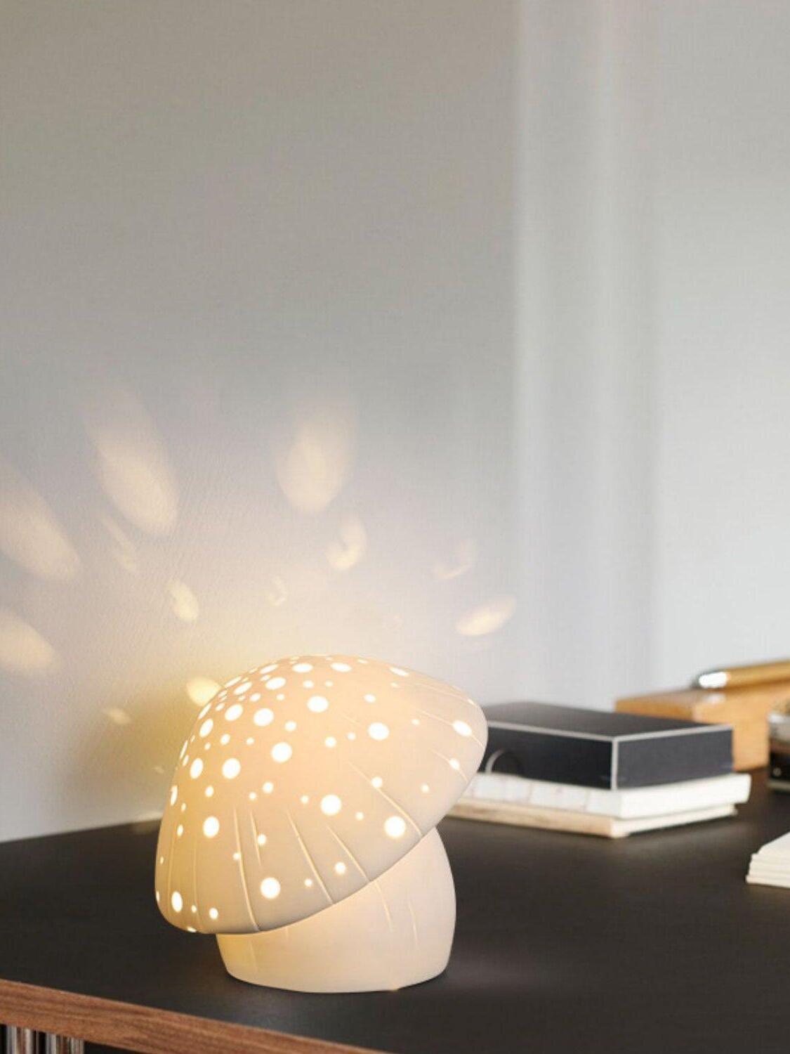 Fungo lamp on a dark console beside stacked books with light spots on the wall