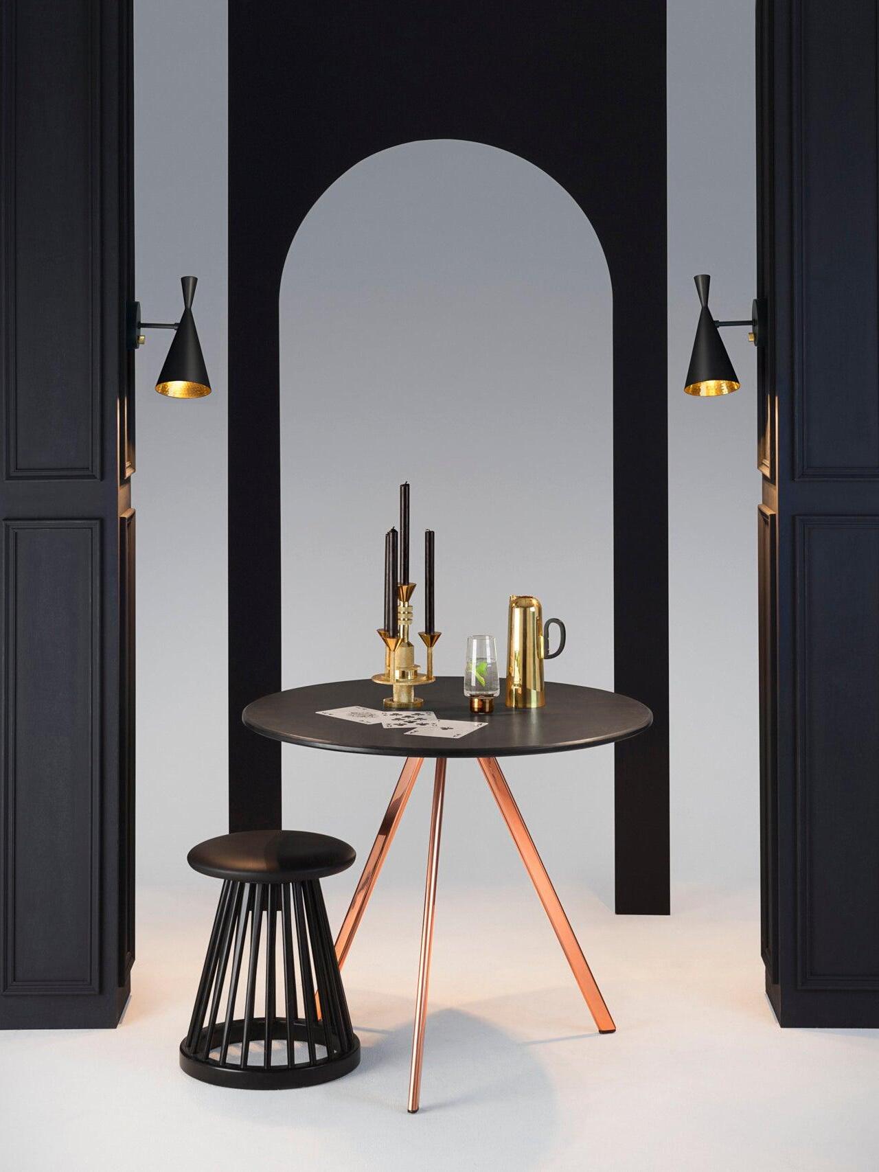 Two separate black cone wall lights in dark dining-room scene