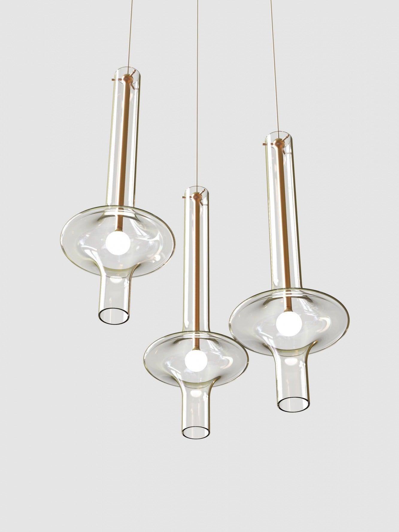Upward view of three clear glass pendants with gold-tone stems, round light points and open lower glass tubes