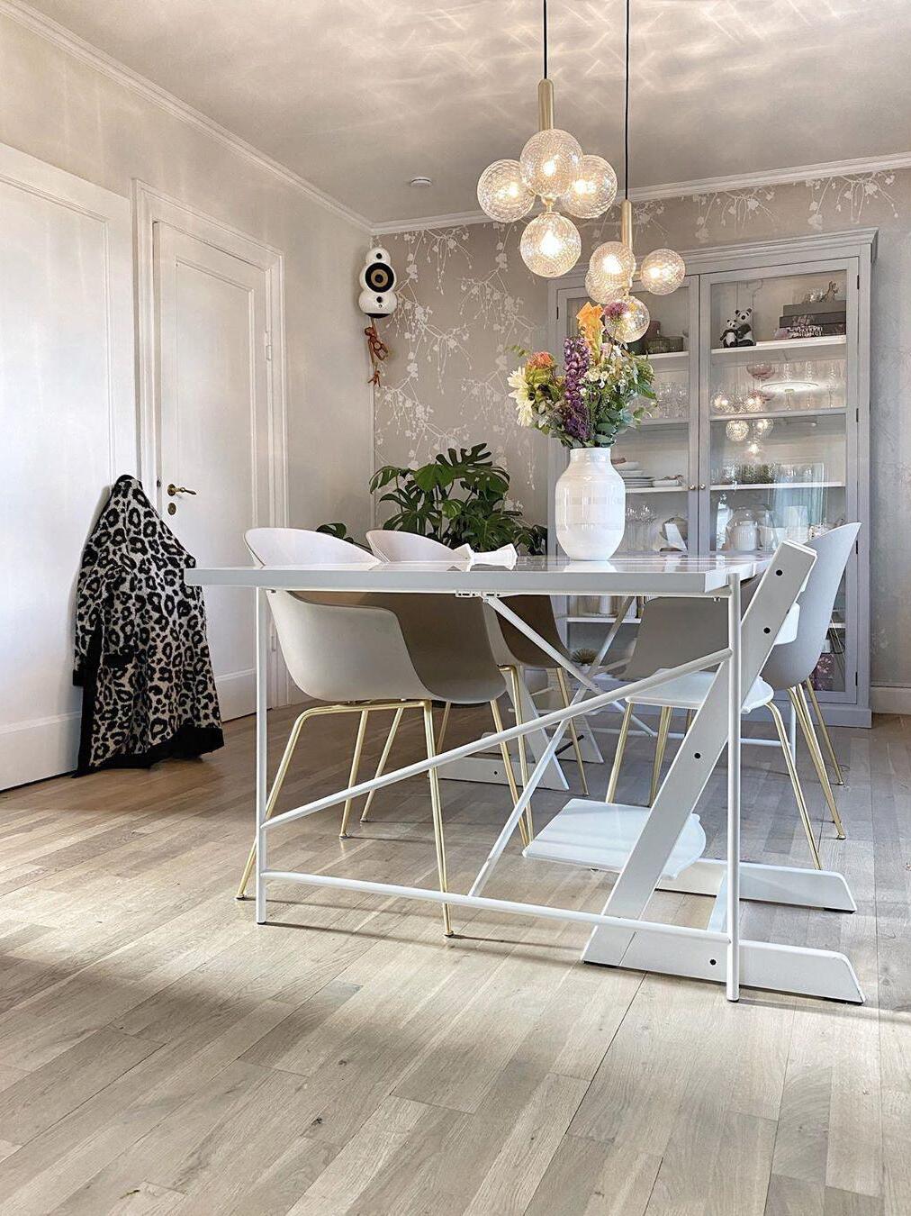 Wide dining-room view with clear globe clusters, ceiling reflections, floral vase and a white high chair