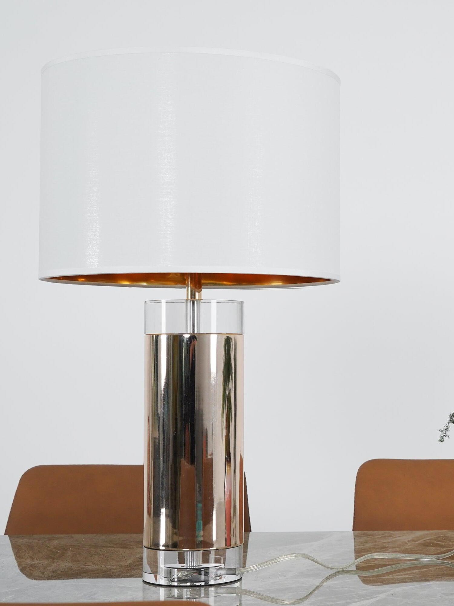 White drum-shade lamp with reflective metallic cylinder, clear base and trailing cord