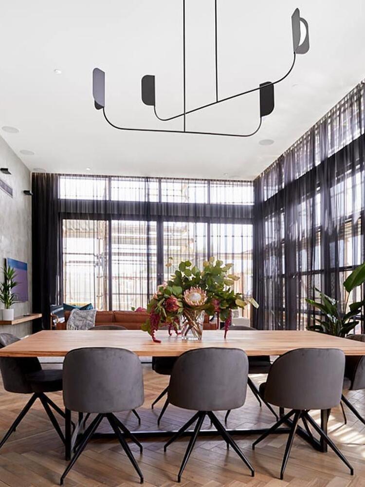 Wide black LEAF chandelier above a dining table