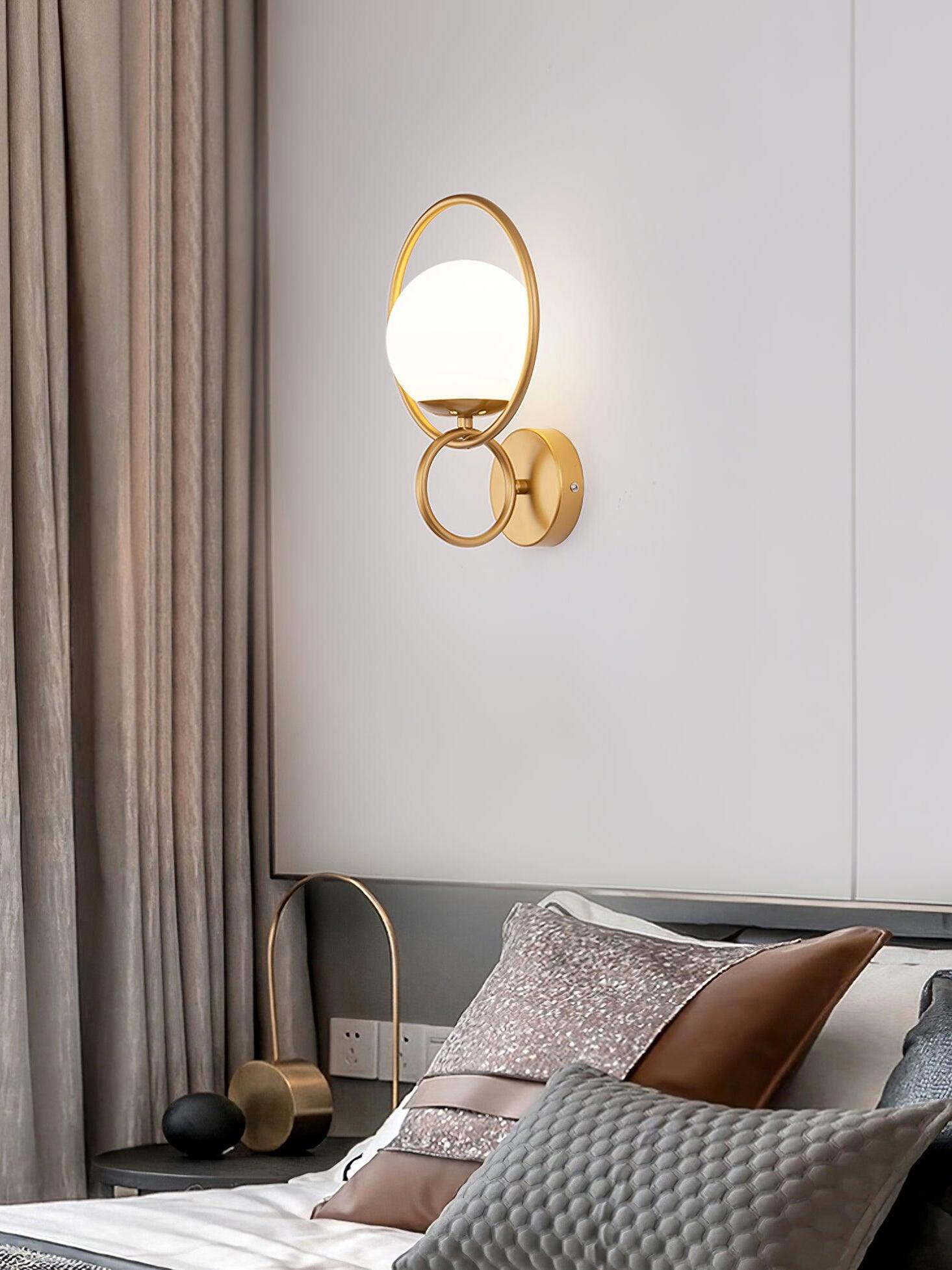 Gold globe wall light beside bedroom curtains