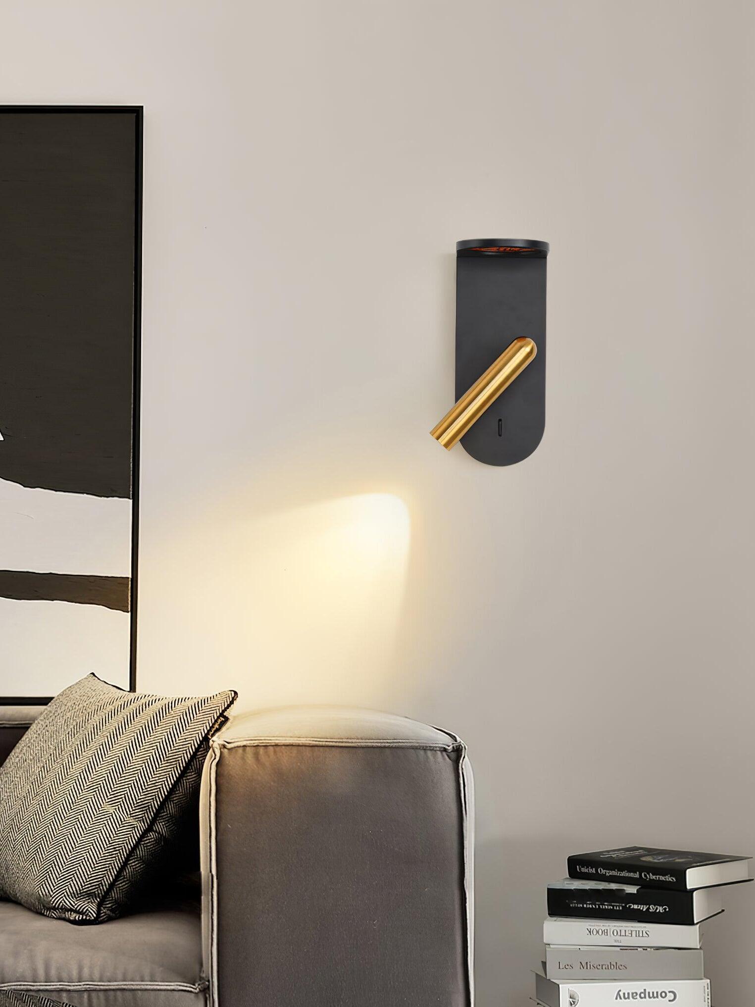 Black Nights wall light with its gold-tone head angled toward a grey chair, with books nearby