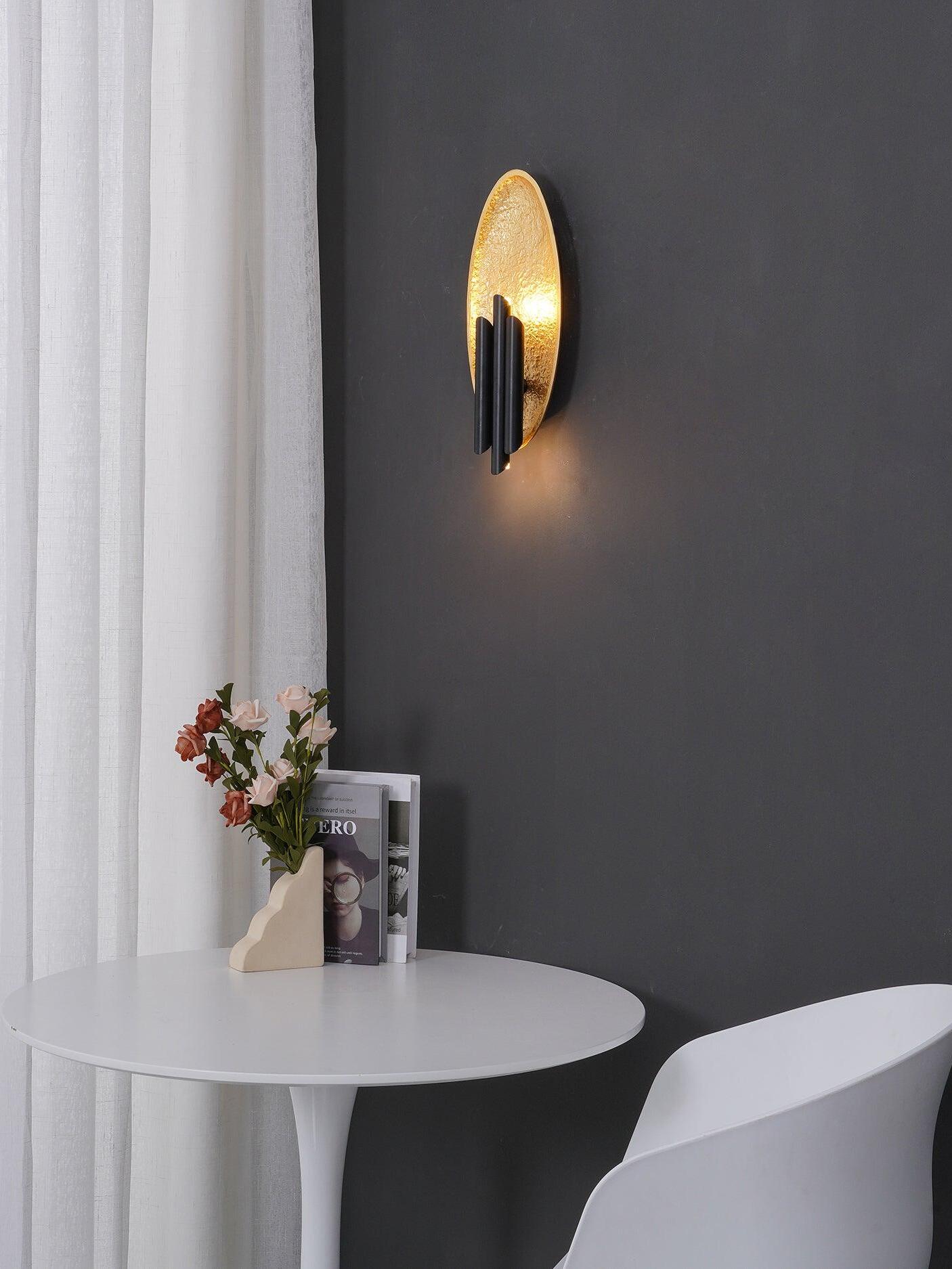 Oval wall sconce above white table and chair beside curtain