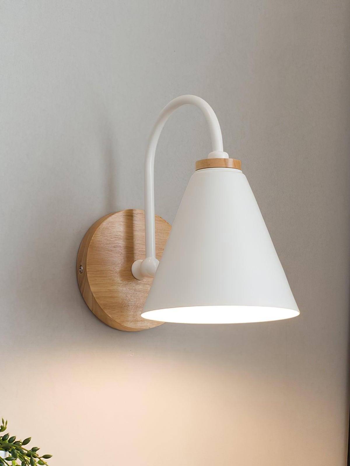 White cone wall lamp lit above a wooden round backplate