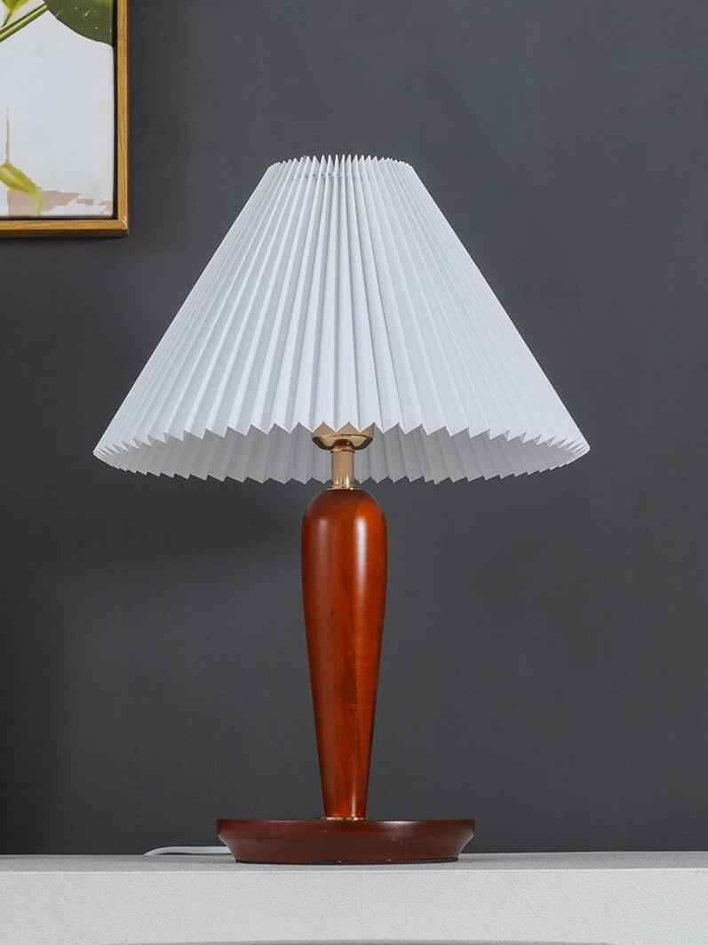 Unlit brown table lamp with white pleated shade against grey