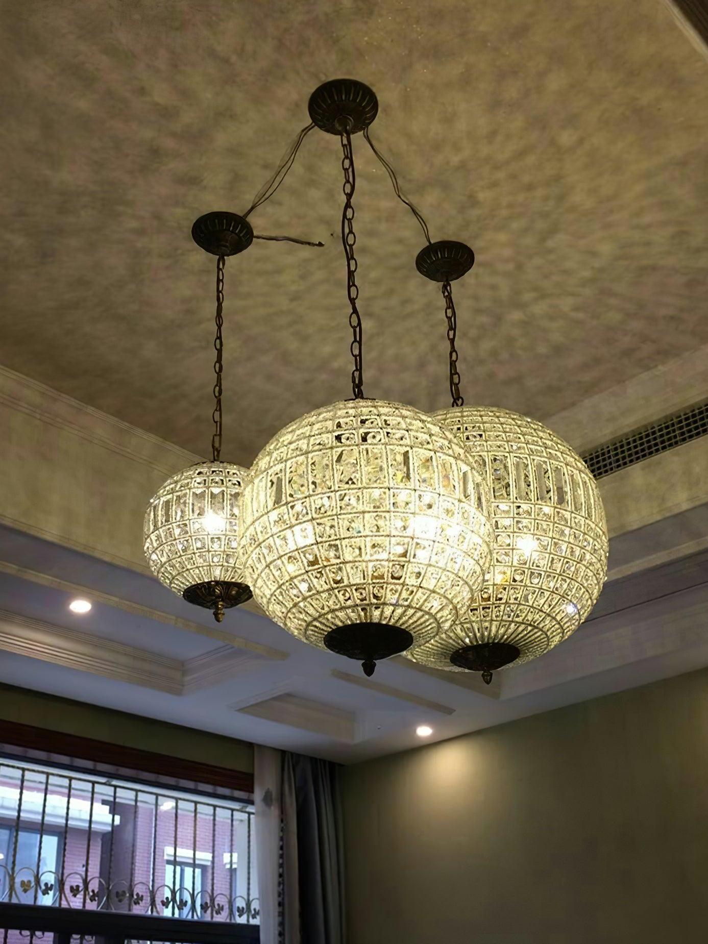 Three glowing crystal globes on separate chains and ceiling canopies with visible wiring between the canopies
