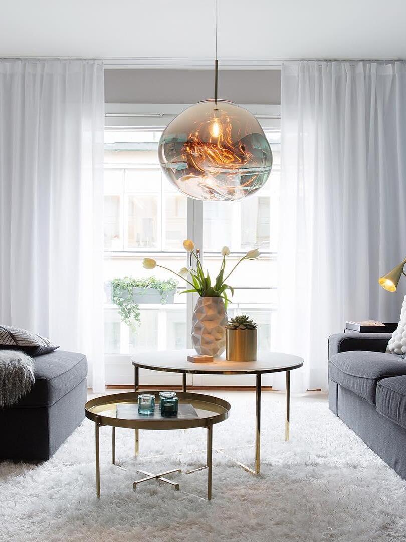 Single reflective pendant above round side tables