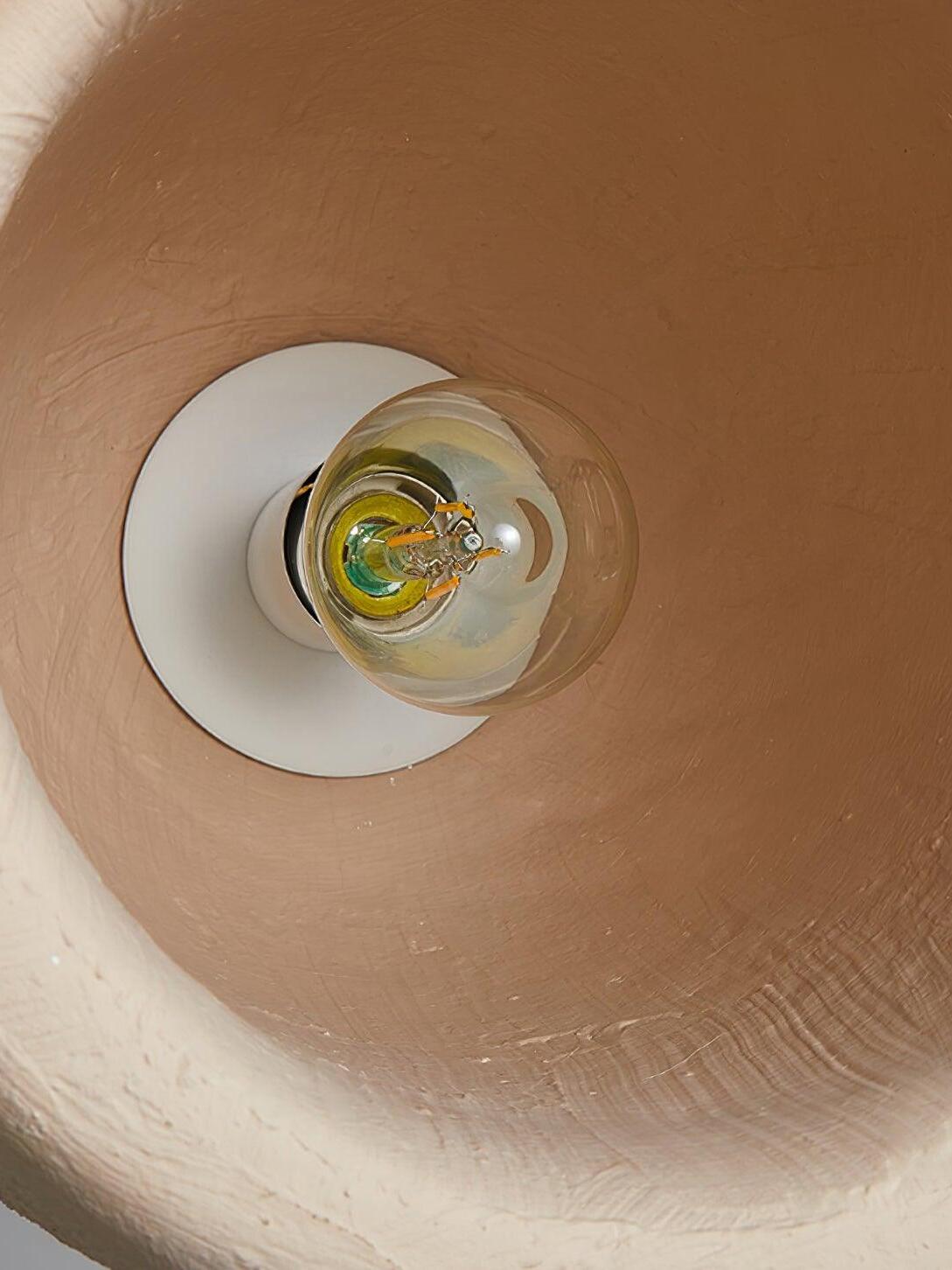Interior shade detail with warm-brown surface, clear round bulb and white holder plate