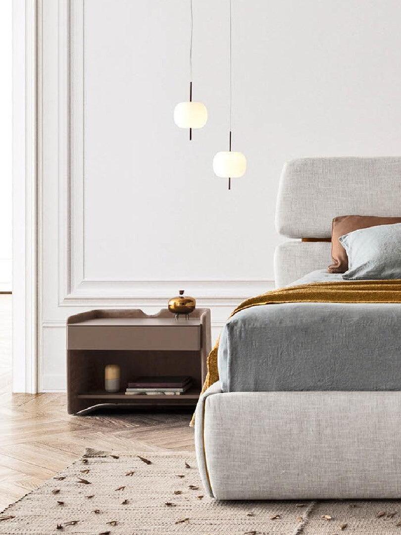 Paired white glass pendants above a bedside table