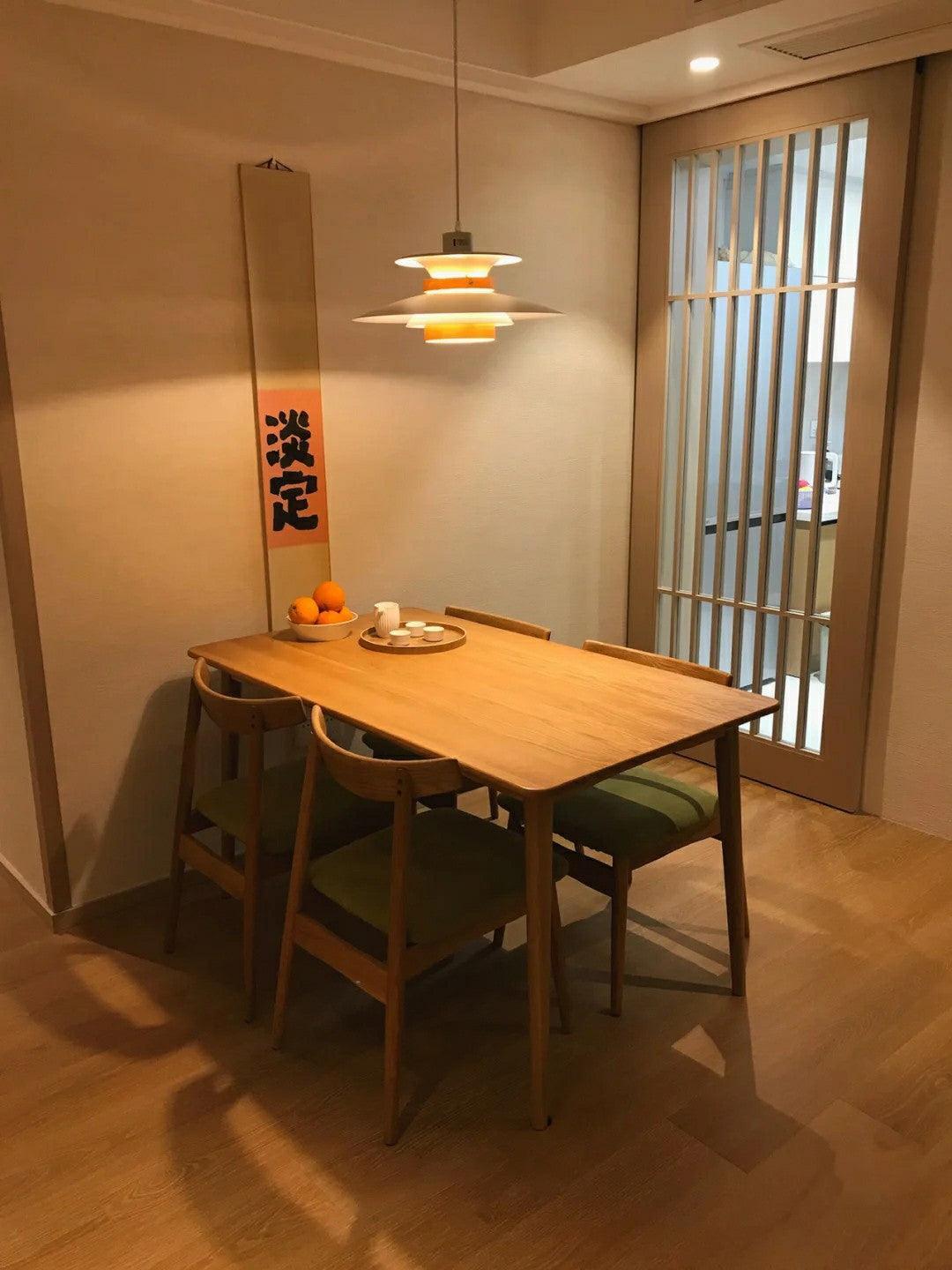 Layered pendant above a wooden dining table beside a sliding door