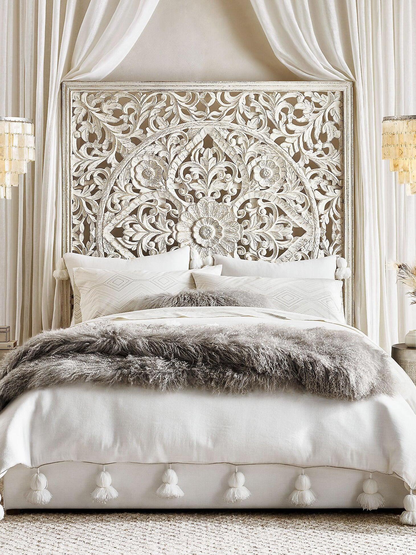 Carved wooden headboard with neutral bedding and cushions