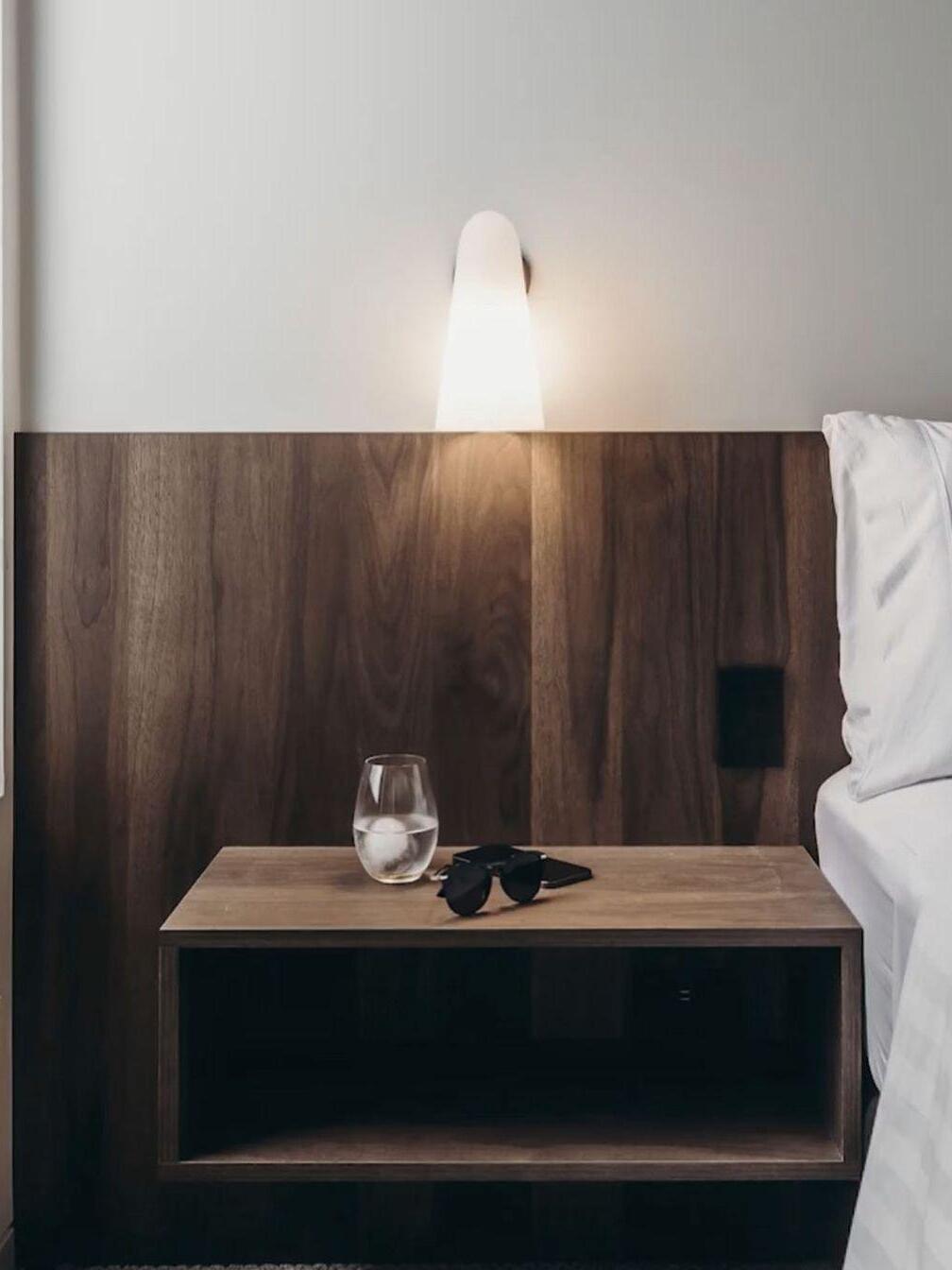 Pale conical shade beside a bed with a wood headboard