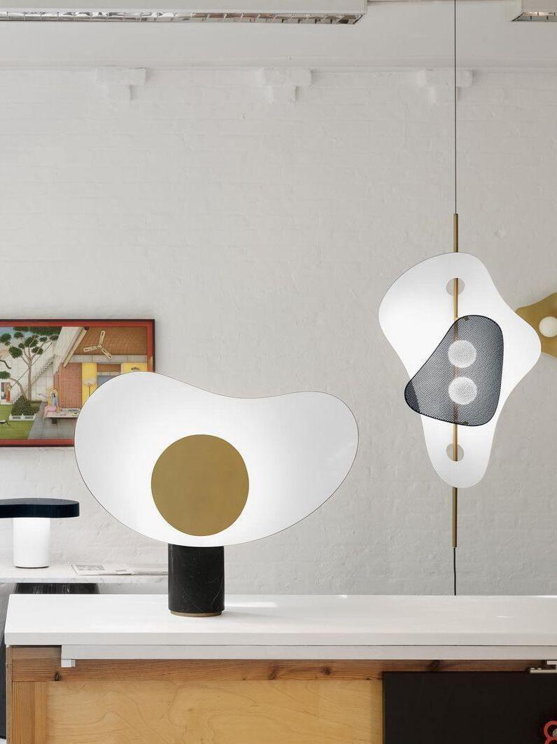 White and gold table lamp on cabinet with separate pendant behind