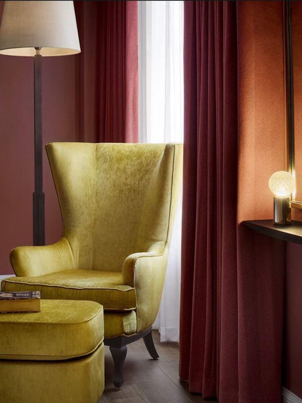 Small globe table lamp near green armchair and separate floor lamp