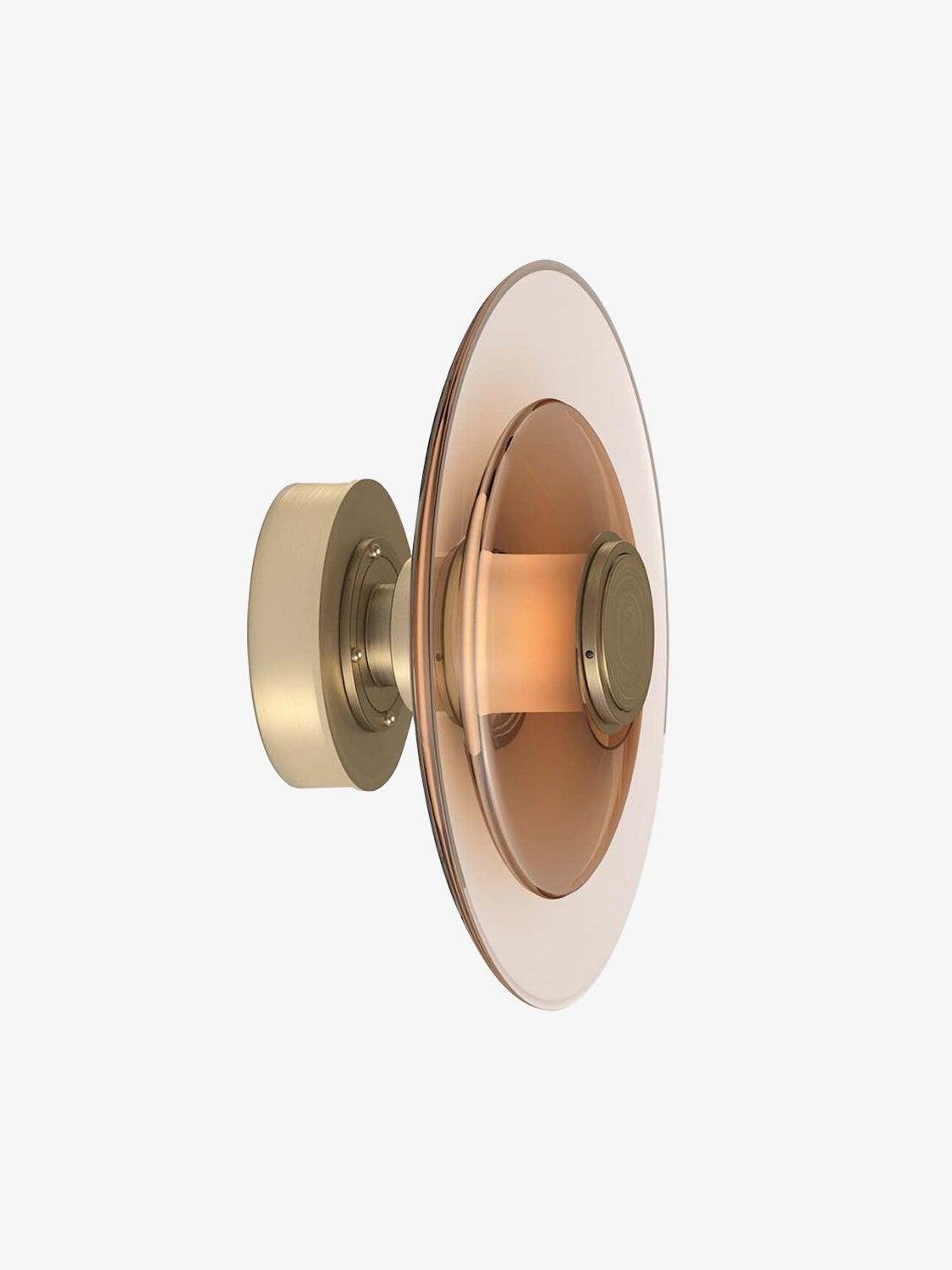Side view of gold wall plate and curved amber glass disc