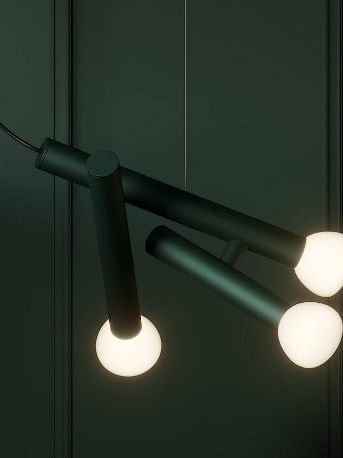 Green multi-head pendant lit against a dark green wall