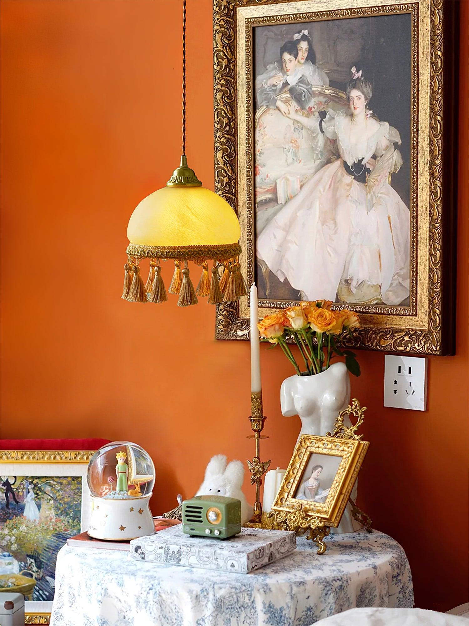 Pendant against orange wall beside framed art