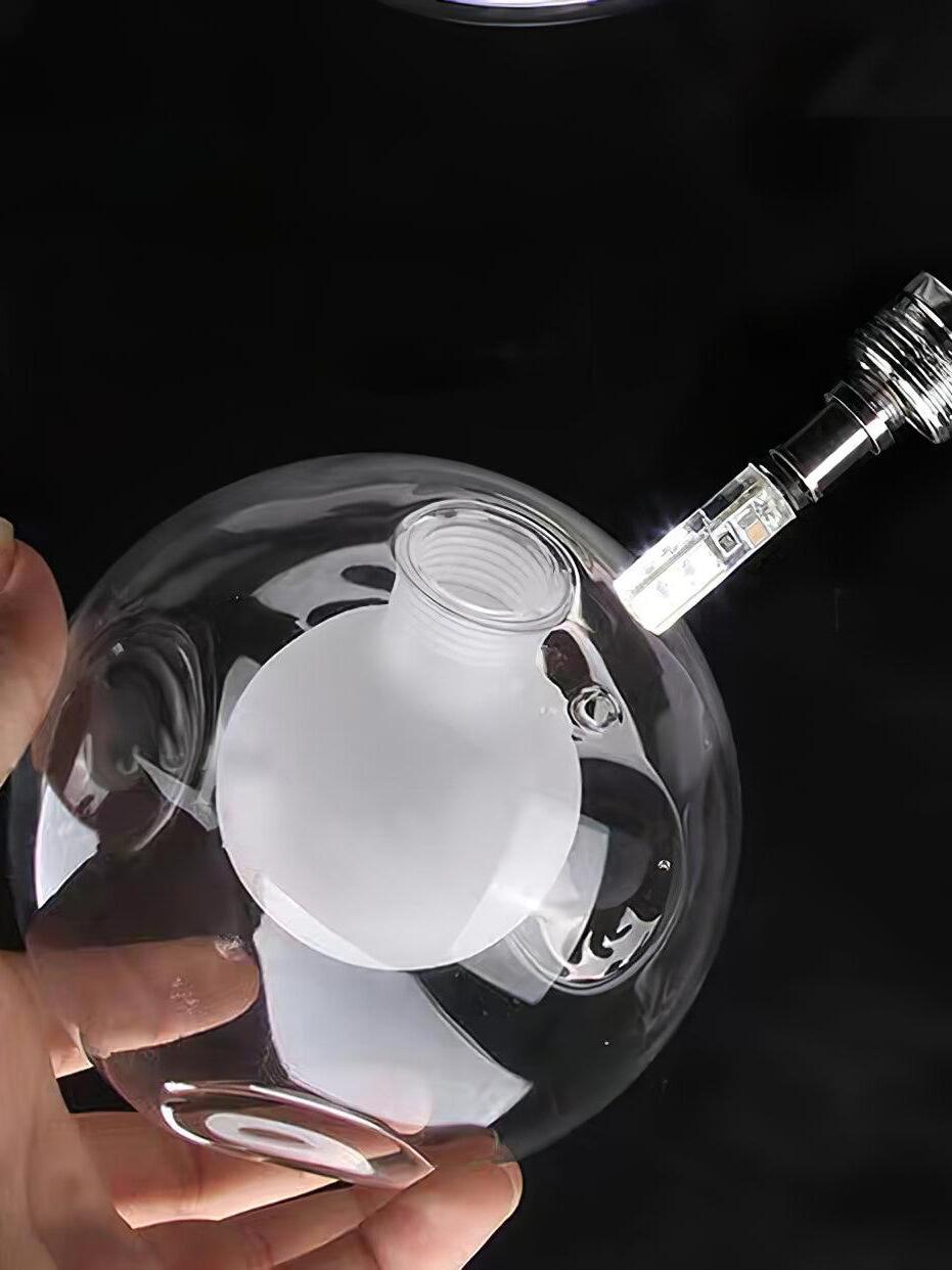 Hand inserting small lamp into clear glass globe holder