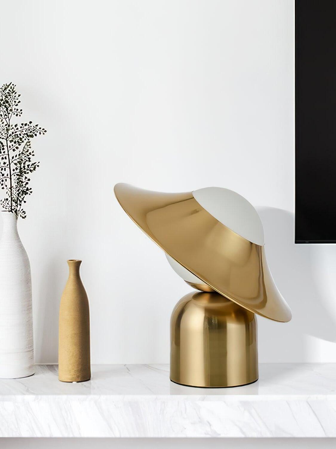Angled gold disc lamp on pale shelf