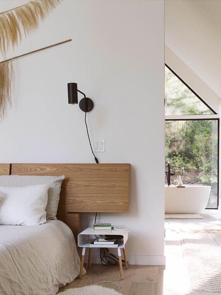 Black wall light beside bed and large window