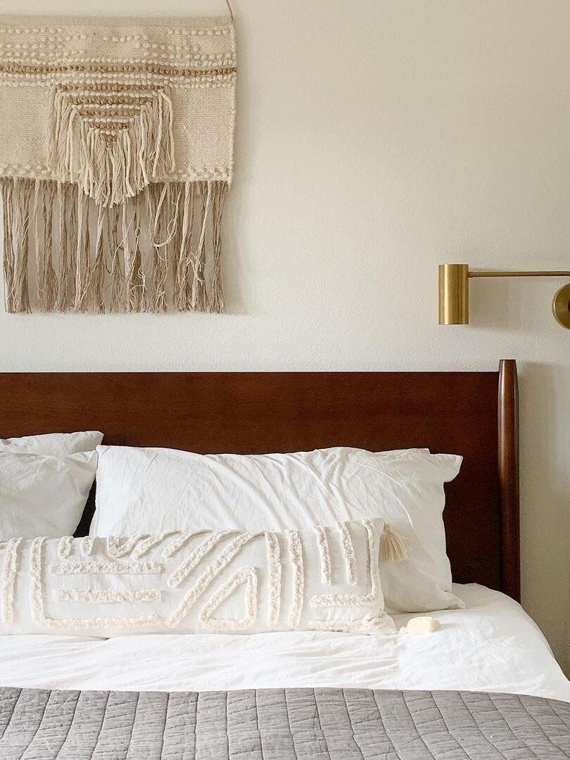 Cropped bed view with brass-tone light and textile hanging