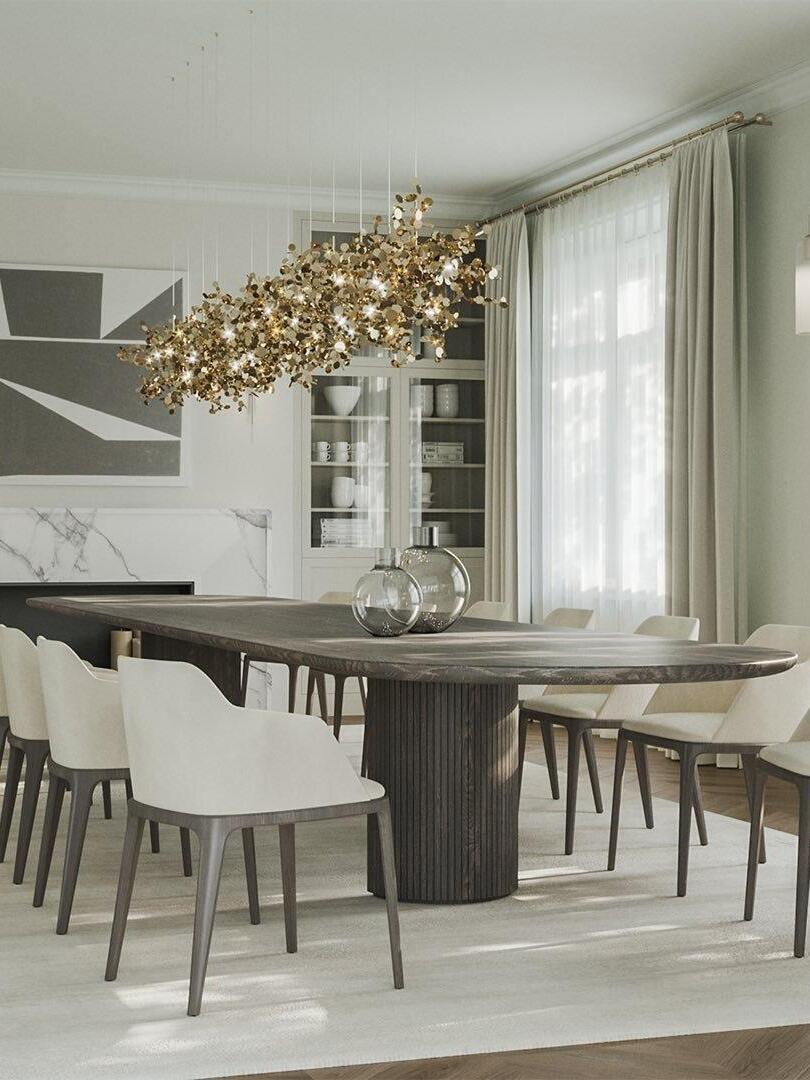 Long gold-toned disc chandelier over a dark dining table