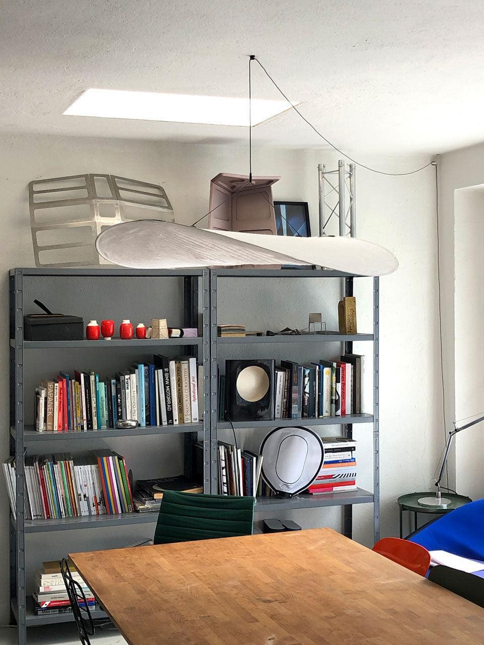 White sweeping pendant above a table and bookshelves