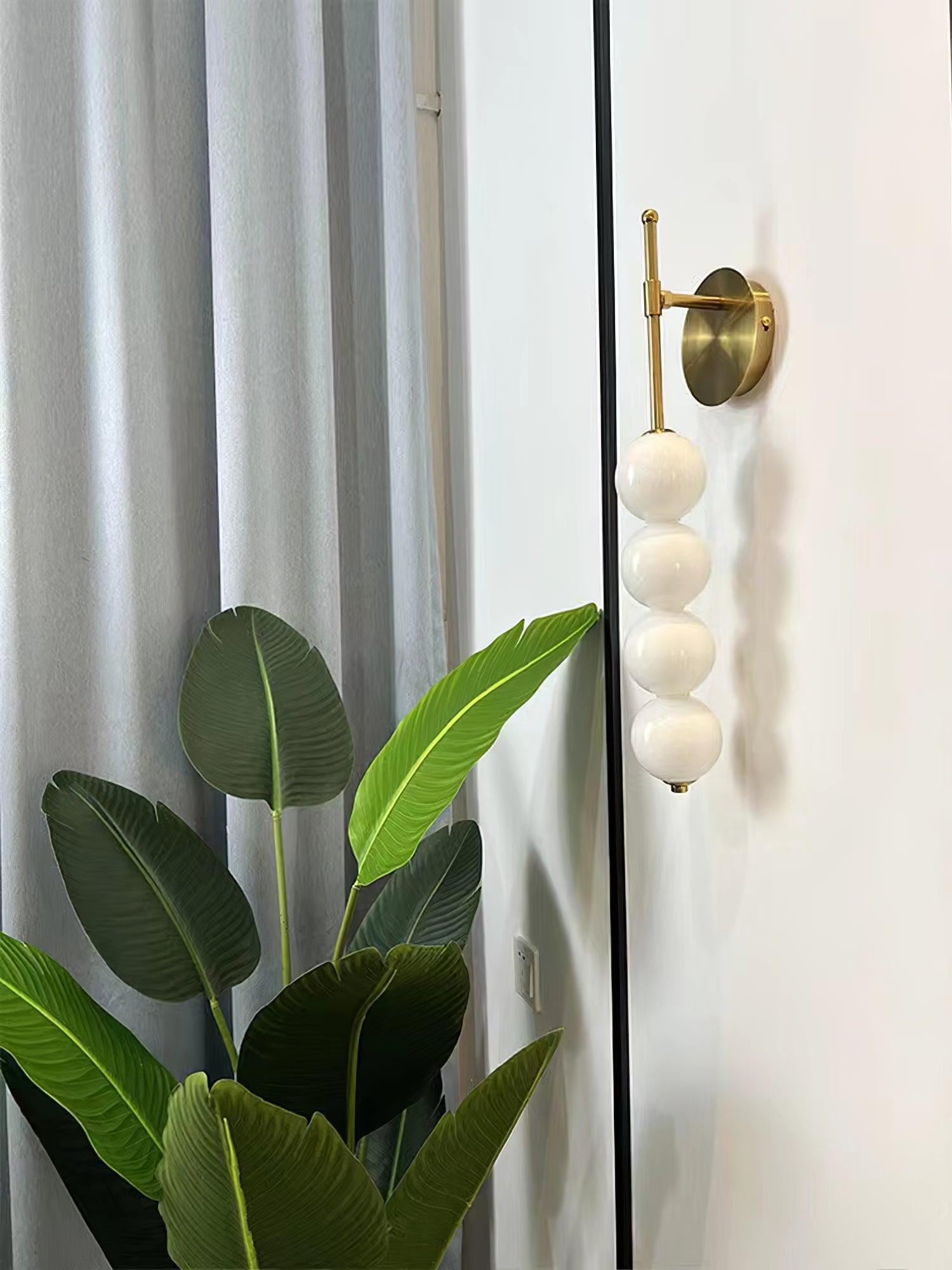 Brass stem wall light beside a leafy plant