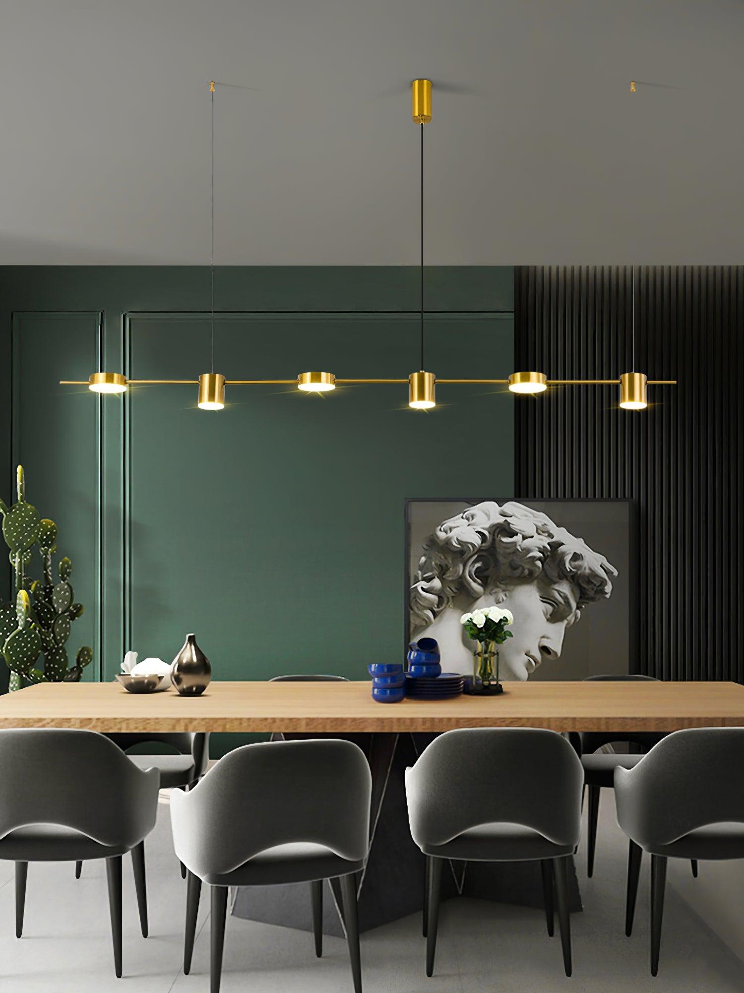 Long gold fixture above dining chairs against a dark wall