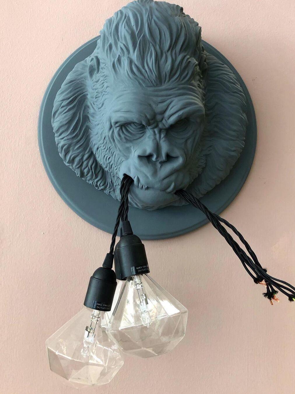 Grey gorilla relief on pink wall with clear diamond-shaped bulbs and black cords